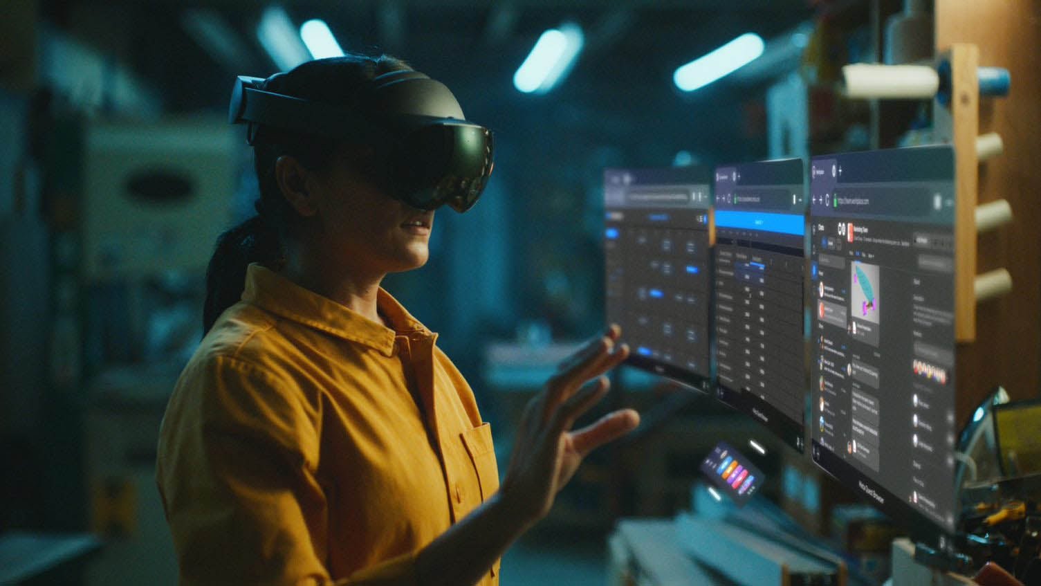 A person wearing a vr headset interacts with a futuristic holographic interface in a lively workshop setting.
