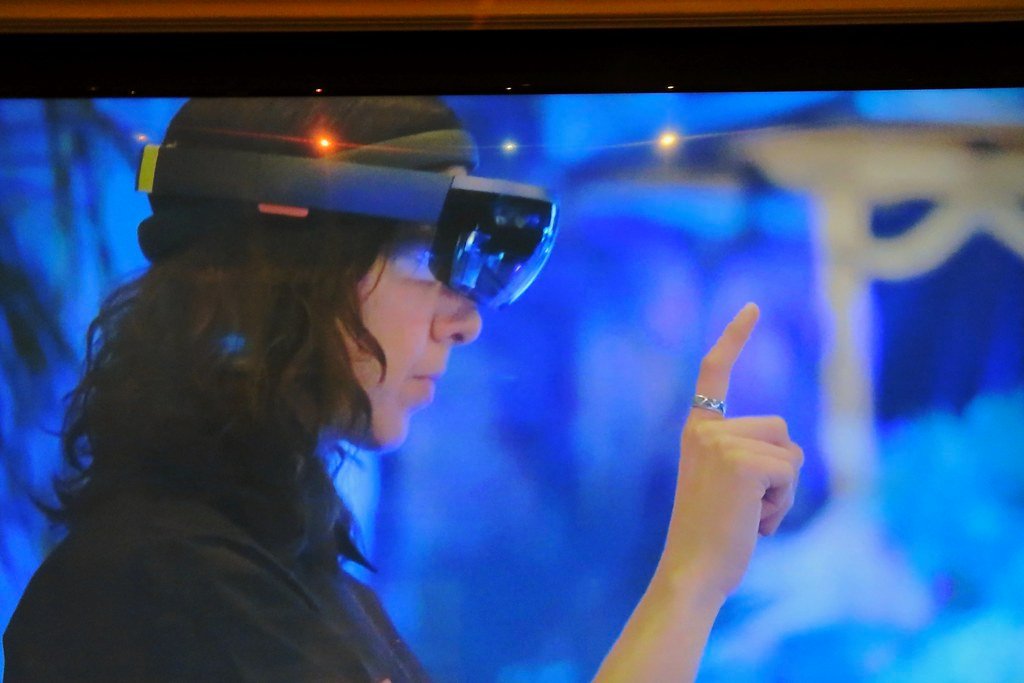 A person interacts with a virtual environment using an augmented reality headset, gesturing with their hand, and potentially manipulating digital elements that only they can see through the device, bringing a futuristic lifestyle alive.